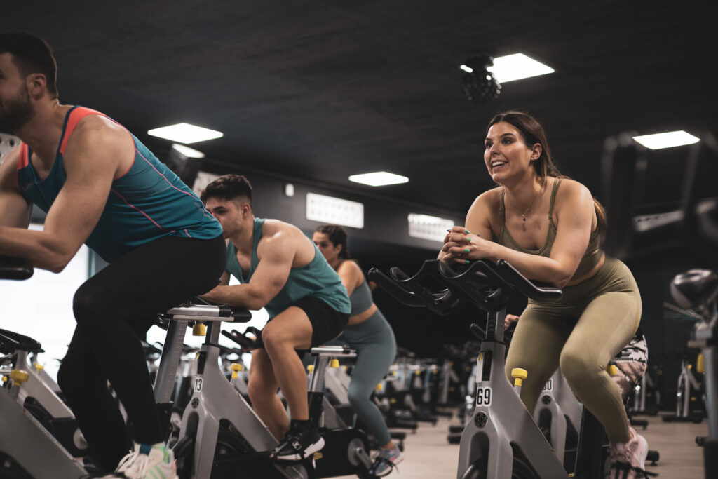 People on bikes in spinning class in modern gym, exercising on stationary bike. group of athletes training on exercise bike